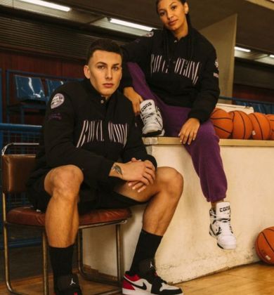 Casal de atletas em roupas esportivas, com basquete ao fundo