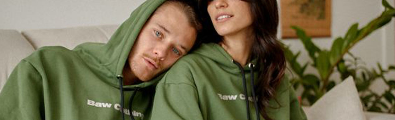Casal usando moletons verdes em um ambiente aconchegante.