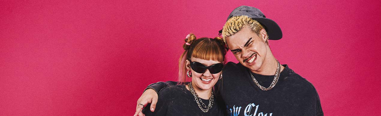 Casal estiloso com roupas streetwear em fundo rosa.
