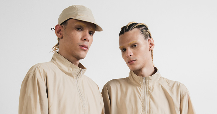 Dois homens com roupas beje posando para a foto.