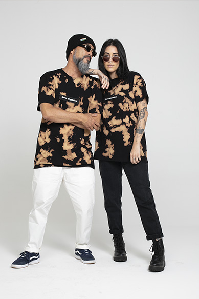 Dupla usando camiseta azul e branca em fundo neutro