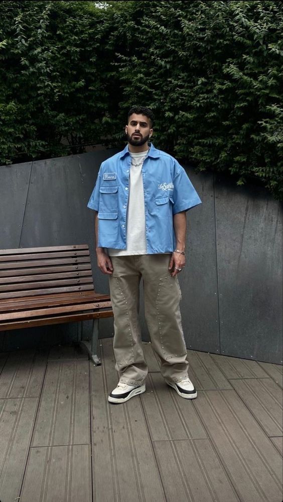 Homem com camisa azul e calças claras em ambiente urbano