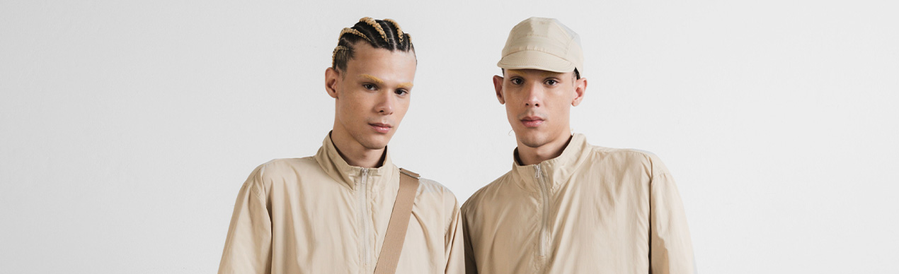 Dois jovens vestindo roupas bejes em estúdio