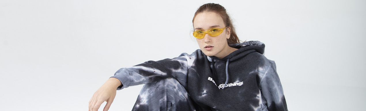 Modelo com moletom tie-dye e óculos amarelos.
