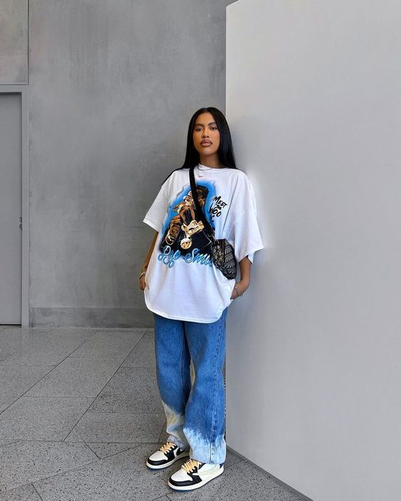 Mulher com camiseta oversized e calça jeans em ambiente moderno