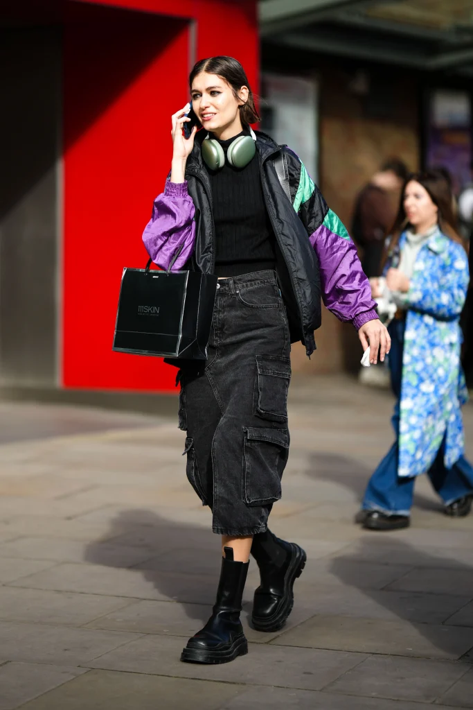 Mulher com fones de ouvido e blusa roxa caminhando na rua.