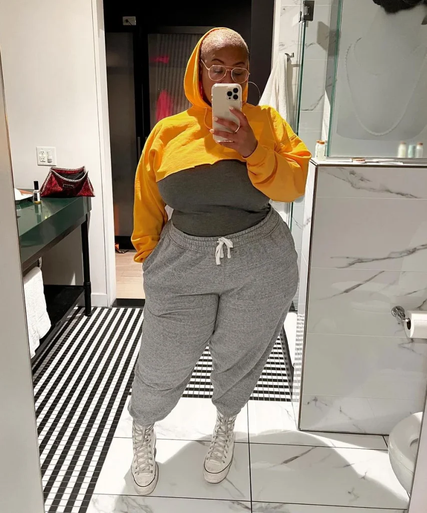 Mulher plus size com moletom amarelo e calça cinza