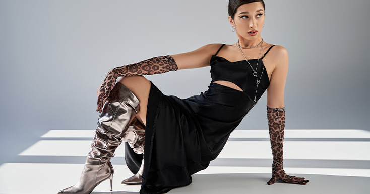 Modelo feminina com vestido preto e botas brilhantes